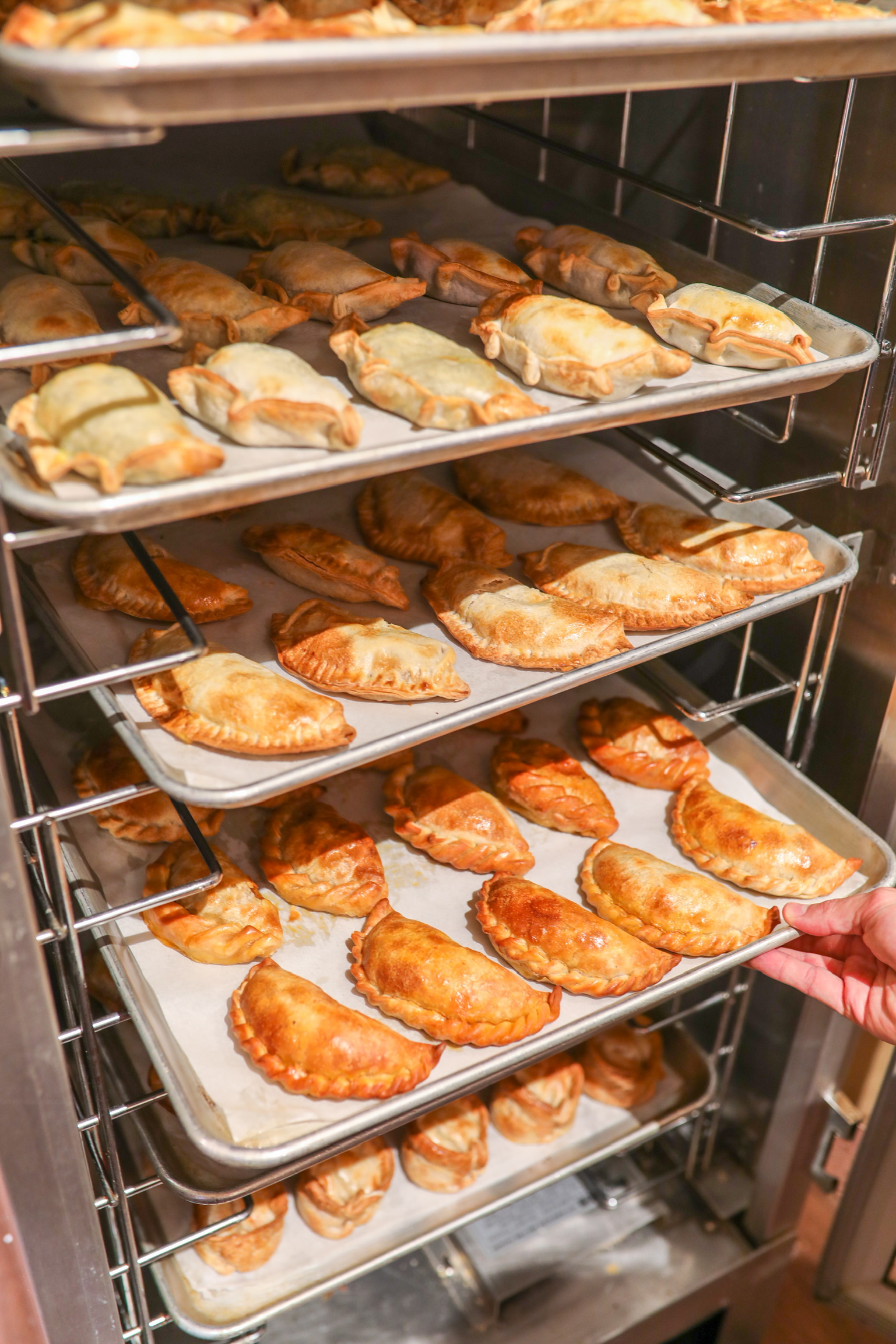 Trays of empanadas coming out of the oven